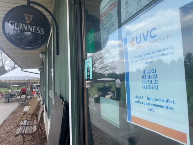 UVC sign at a restaurant window with a Guinness sign nearby and outdoor chairs 