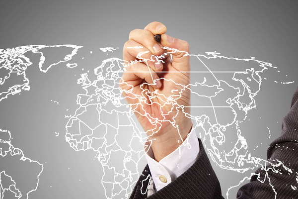 Man in suit right hand writing on a white outline of a map of the world